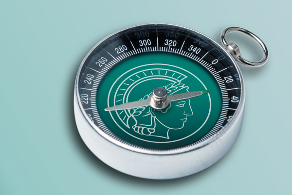silberner Kompass mit grüner Kompasskarte vor grünem Hintergrund
