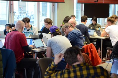 Wissenschaftler*innen des Projekts nextGEMS sitzen während eines Hackathons mit ihren Laptops in Gruppen zusammen.