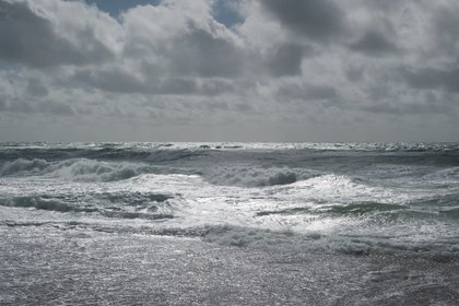 Wellen am Nordseestrand, der Himmel ist bedeckt.