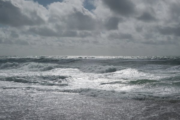 Wellen am Nordseestrand, der Himmel ist bedeckt.