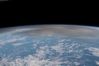 Photograph of the Earth shot from the International Space Station with visible volcanic ash cloud