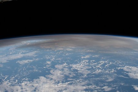 Photograph of the Earth shot from the International Space Station with visible volcanic ash cloud