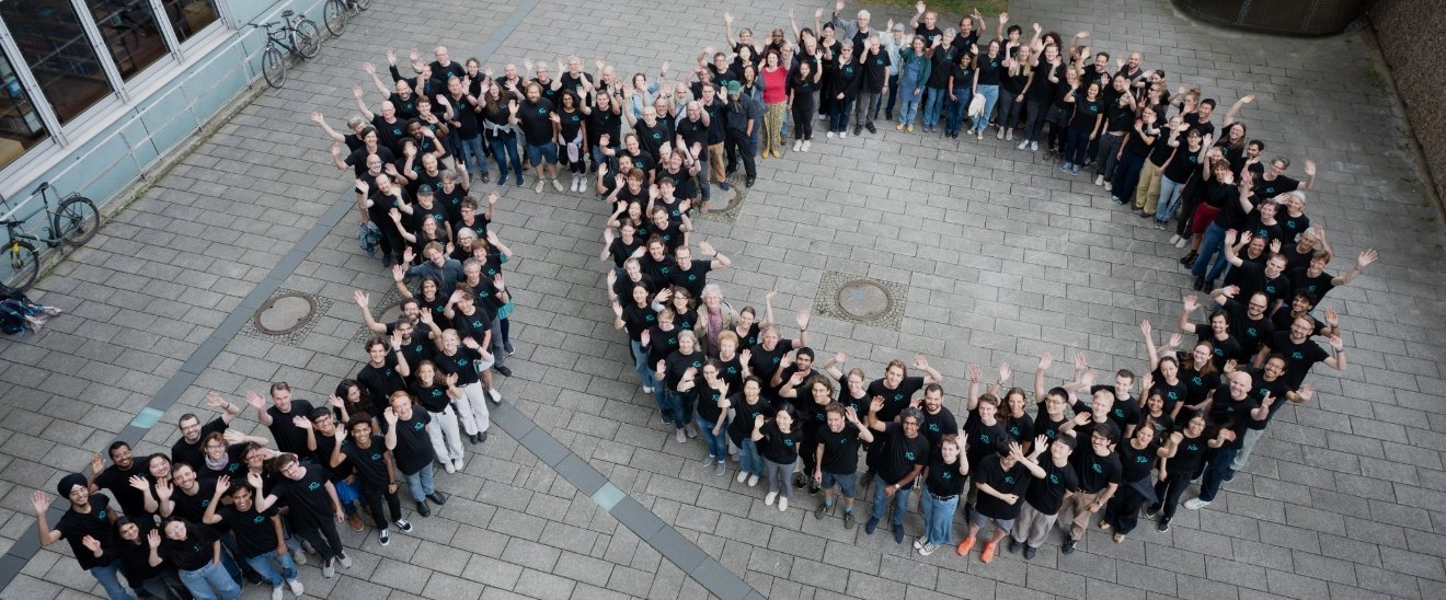 Credit: MPI-M Die Zahl 50, geformt vor dem Institutsgebäude von allen MPI-M Mitarbeitenden, die meisten tragen das schwarze Jubiläums-T-Shirt.