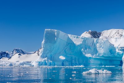Photo of massive icebergs in Antarctica in front of a clear blue sky.