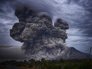 Volcanic eruption with towering ash cloud, forest and road in the foreground
