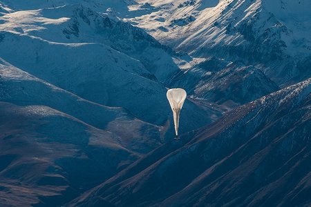 Schwebender Überdruckballon vor schneebedecktem Bergpanorama