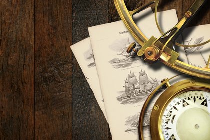 Historic navigation set on a wooden table: A golden sextant, a compass, and old illustrated pages showing sailing ships with the German title "Schiffstypen" are placed on dark wood.