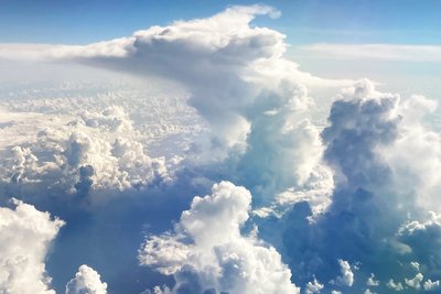 High clouds pile up against a blue sky, view from above.