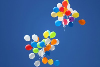 Farbenfrohe Luftballons steigen in einen blauen Himmel