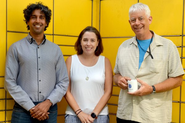 3 people in front of a yellow background look towards the camera